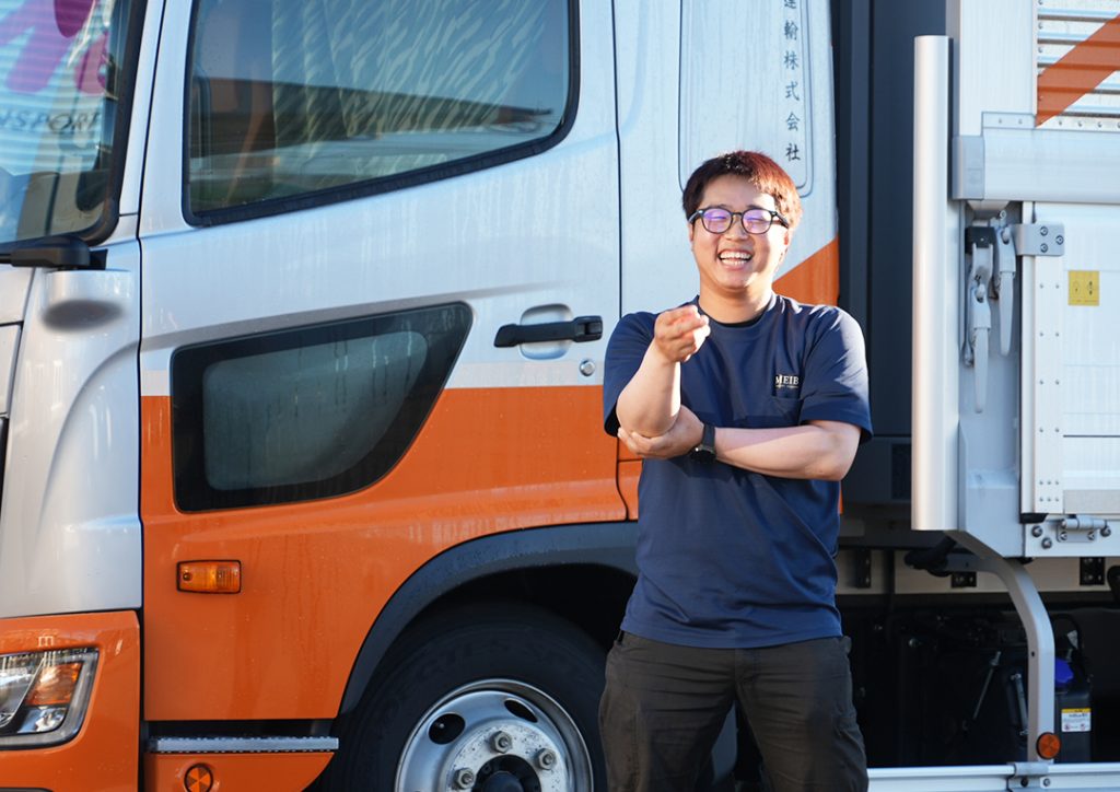 トラックの横でポーズをとるドライバーの様子